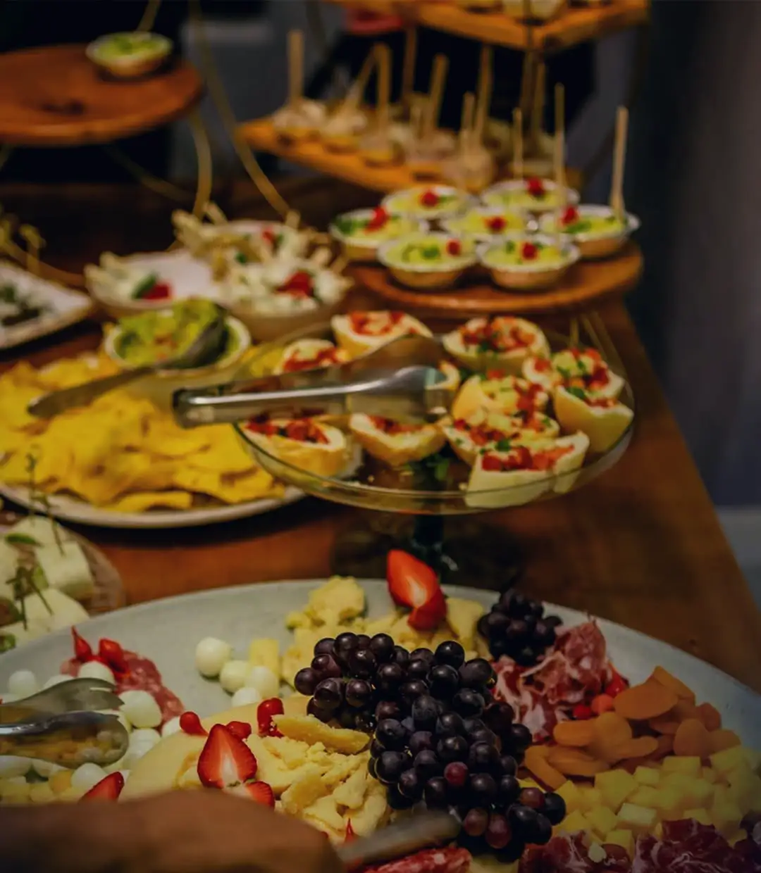A mesa de comida da casa: canapés, frios, queijos, uvas e morangos
