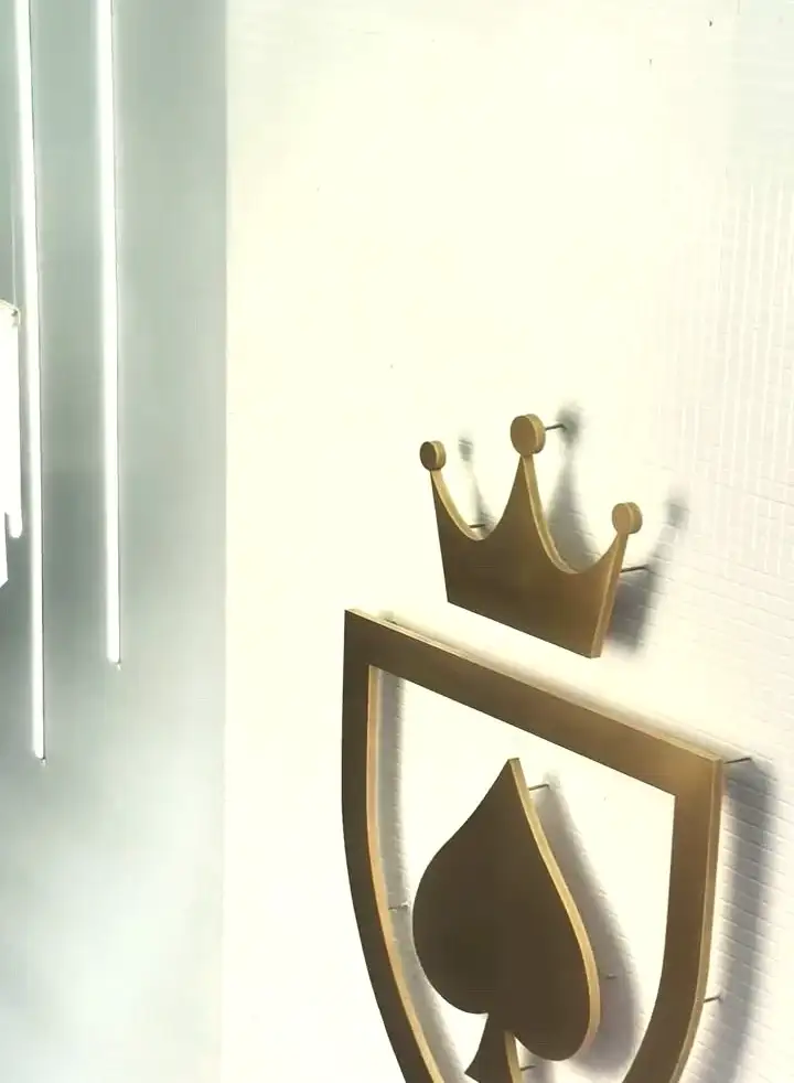 O escudo dourado do Monaco, com coroa e espada, em relevo na parede de pastilhas da casa