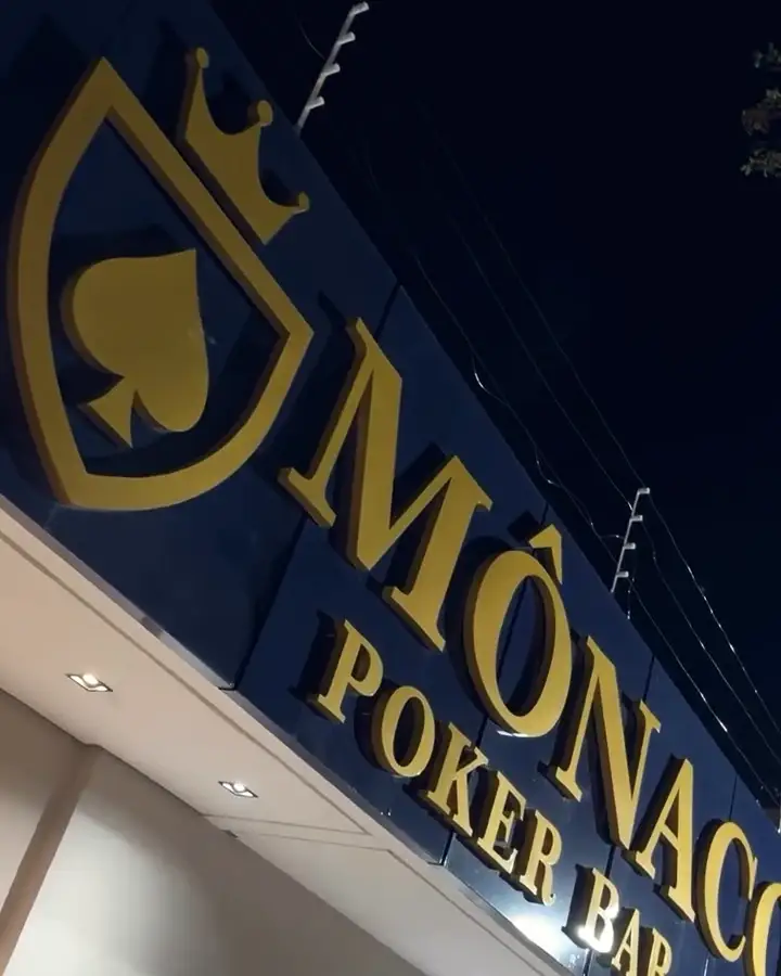 O letreiro do Monaco à noite, visto de baixo: o escudo e o nome em dourado sobre o azul
